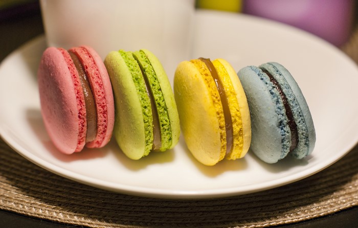 Four colorful macarons on a white plate