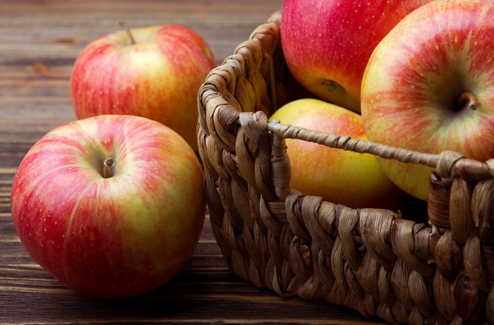 Apples in a wicker basket on a wooden table