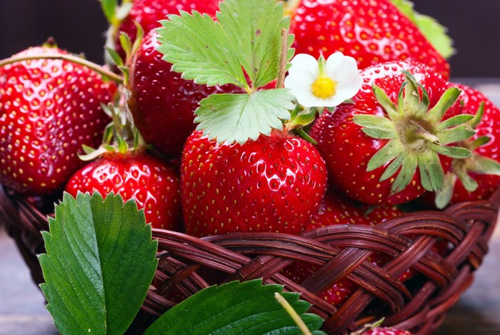 Basket of fresh strawberries with leaves and flower