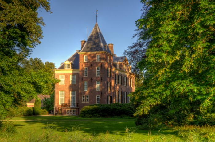 Brick mansion with tower surrounded by trees in Laren, Netherlands