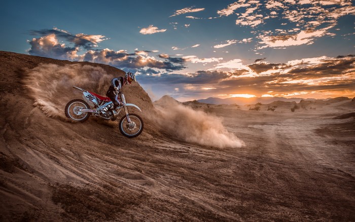 Motocross rider on a dirt track at sunset