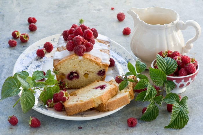 Raspberry pound cake with a pitcher and bowl of raspberries