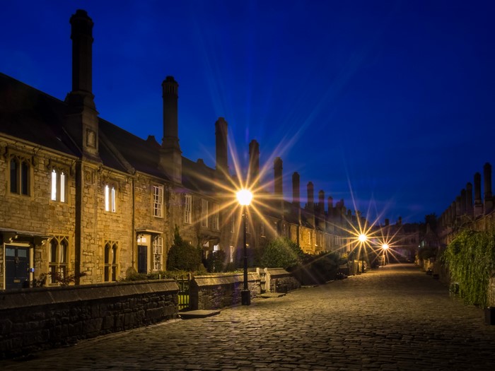 Street lights on a cobblestone street in Wells, England at night