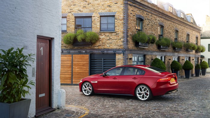 Red Jaguar XE parked on cobblestone street