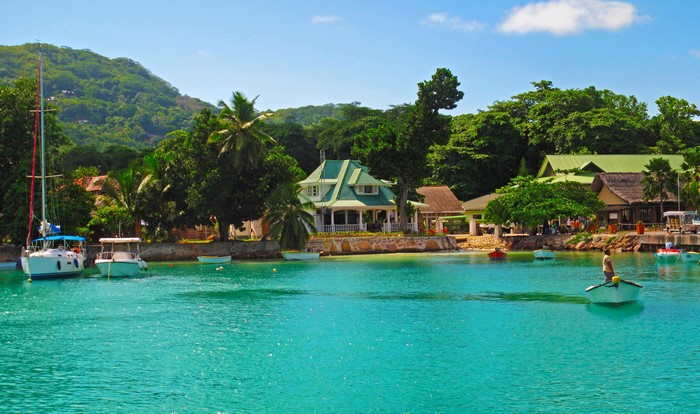 Tropical resort with boats on turquoise water and lush green hills
