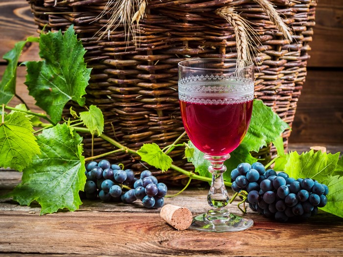 Glass of red wine with grapes and basket