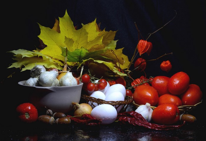 Still-life with tomatoes, garlic, eggs, and autumn leaves