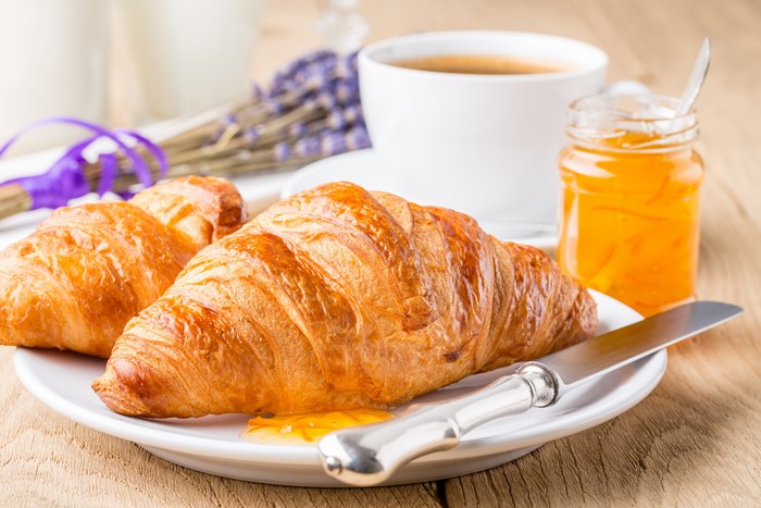 Croissants with jam and coffee on a wooden table