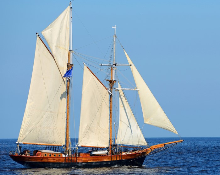 Wooden sailing ship with white sails on the sea