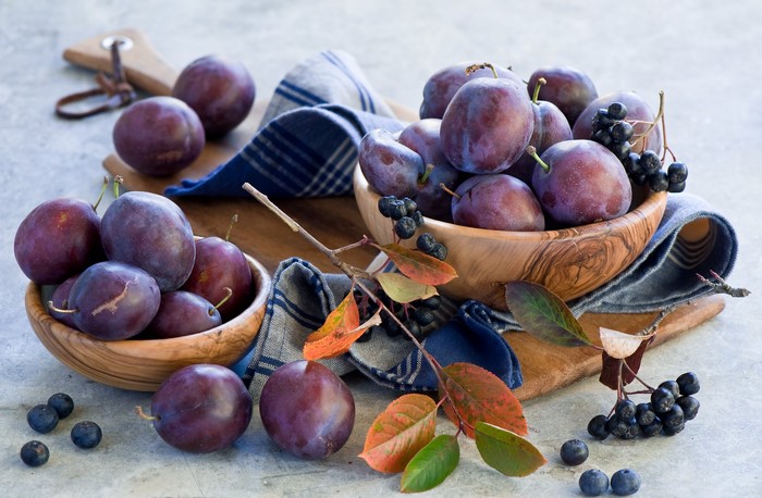 Plums and Aronia berries in wooden bowls