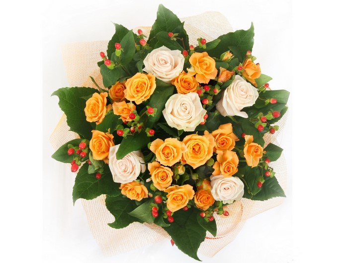 Bouquet of orange and cream roses with green leaves and red berries