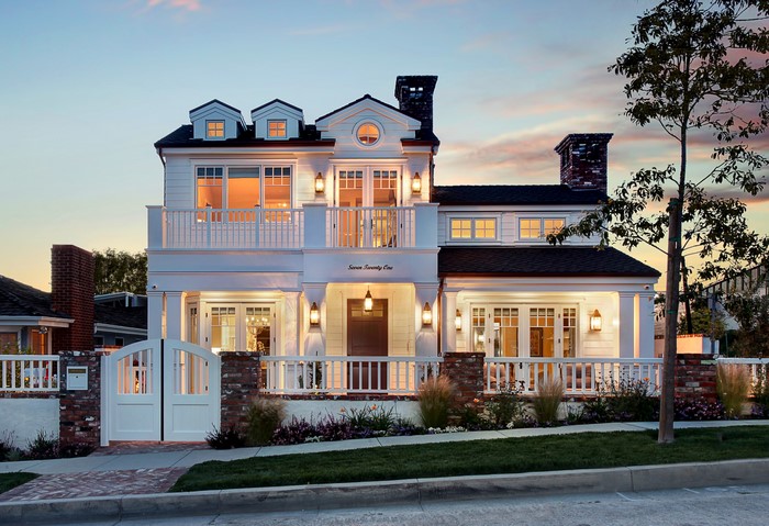 White two-story house with brick accents and a white gate
