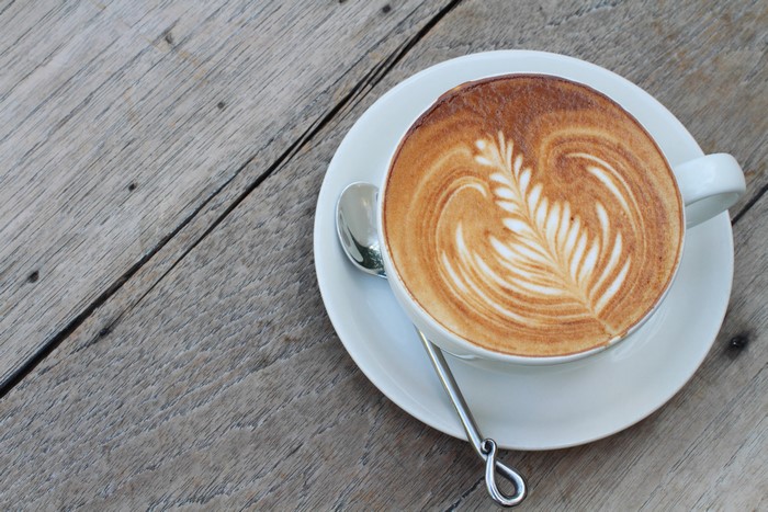 Latte art coffee cup with saucer and spoon