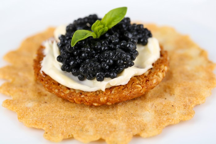 Caviar on a cracker with butter and basil