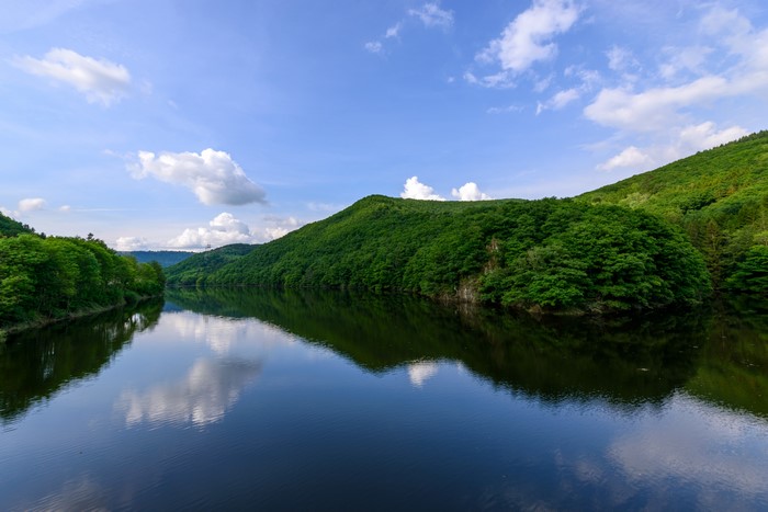 River and green hills under a blue sky with clouds