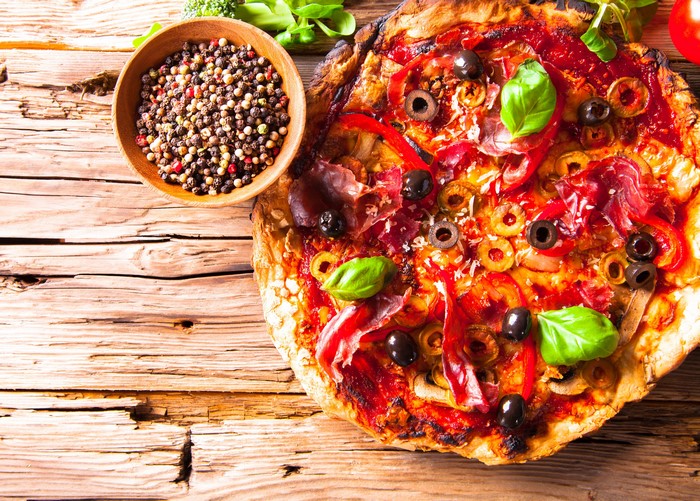 Pizza with olives, prosciutto, and spices