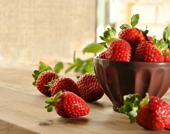 Strawberries in a bowl on a wooden table