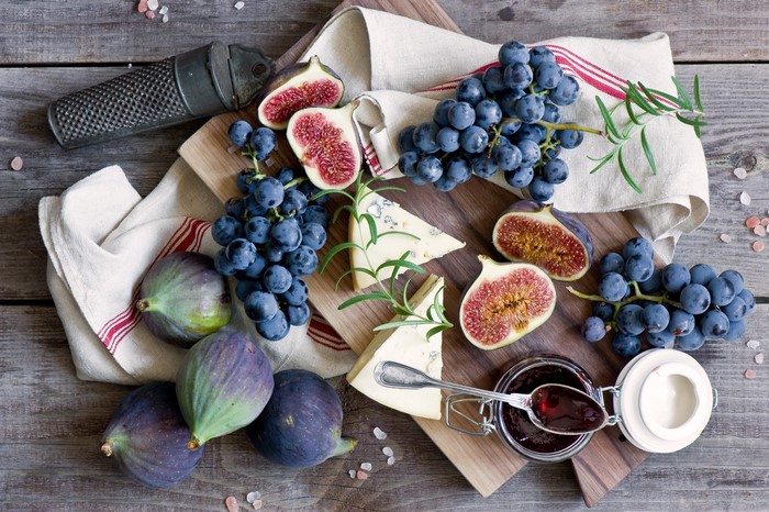 Still-life of grapes, figs, cheese, and jam