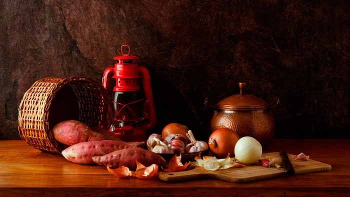 Still life with sweet potatoes, onions, garlic, and lantern