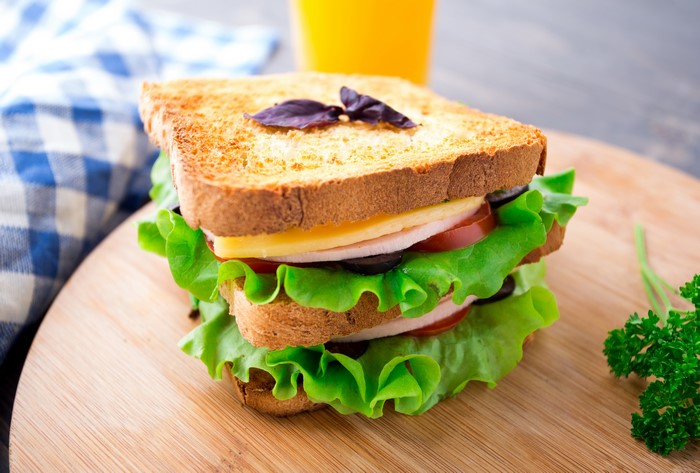 Sandwich with lettuce, cheese, ham, tomato, and olives