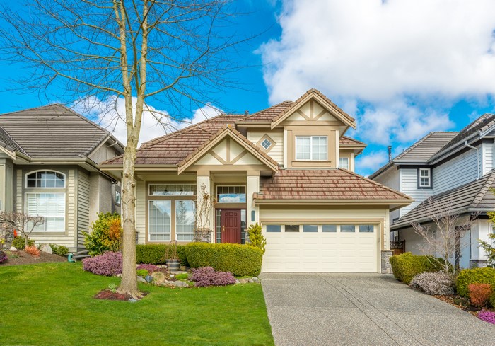 Suburban house with manicured lawn and blue sky