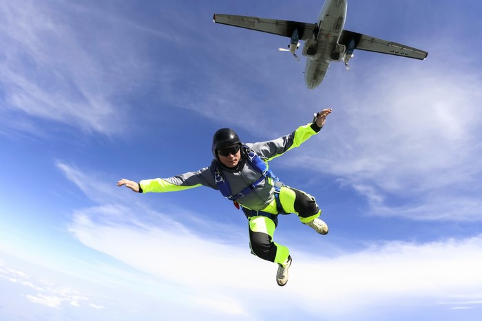 Skydiver in mid-air with airplane above