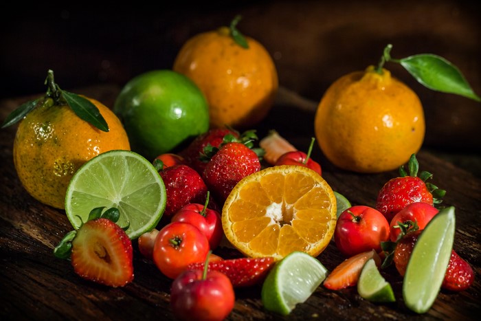 Assortment of fresh fruits including oranges, limes, and strawberries