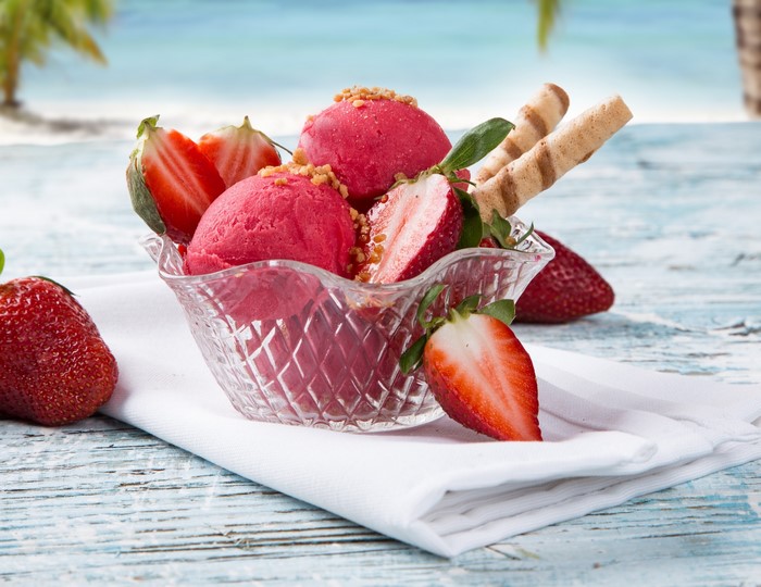 Strawberry ice cream sundae with wafer cookies on a beach background