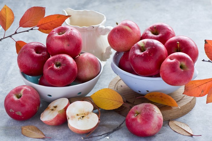 Red apples in bowls with autumn leaves
