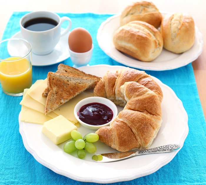 Breakfast with croissants, toast, cheese, jam, and coffee