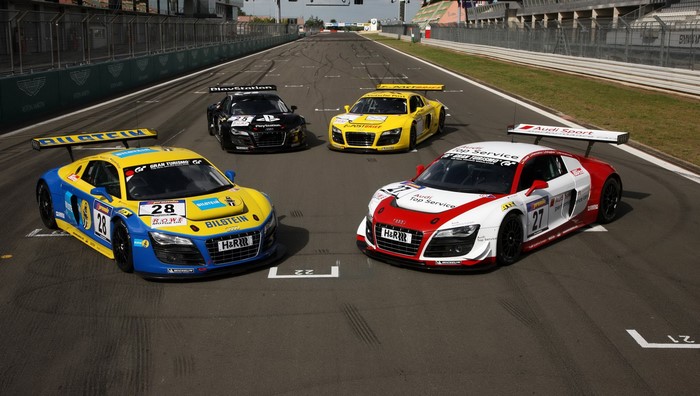 Four Audi R8 LMS race cars on a track