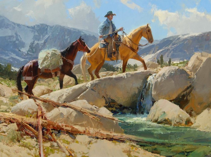 Cowboy with horses crossing a stream in mountains