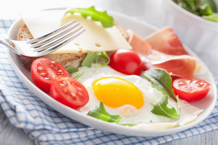 Fried egg with prosciutto, cheese, tomatoes, and bread