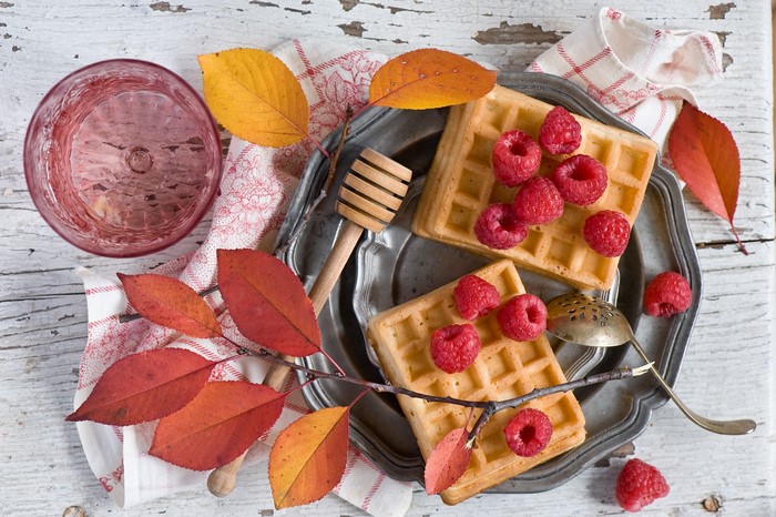 Waffles with raspberries and autumn leaves on a plate