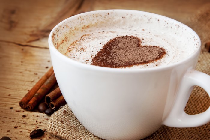 Coffee cup with heart shape and cinnamon sticks