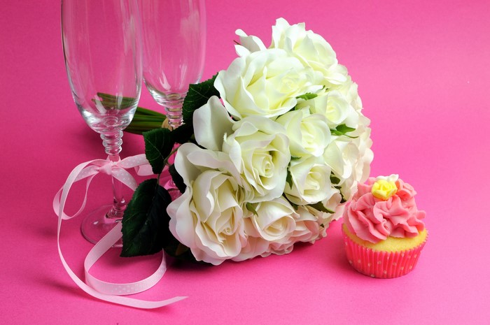 White roses bouquet with champagne glasses and cupcake