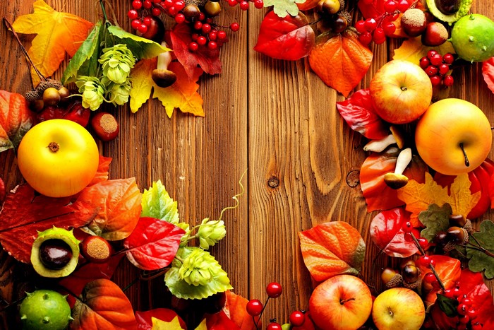 Autumn harvest with apples, leaves, and berries on wood
