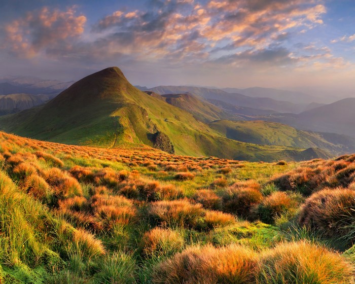 Mountain landscape with golden grass and clouds at sunset