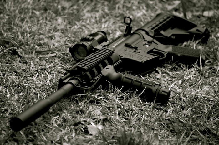AR-15 rifle with scope and flashlight on grass