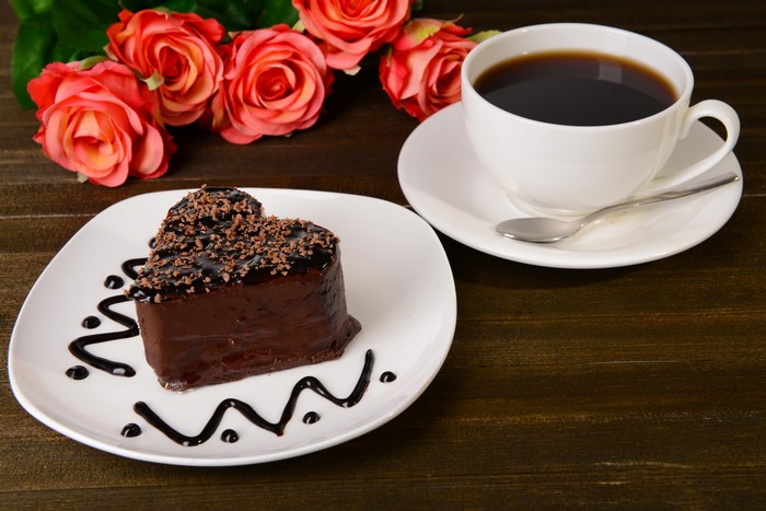 Heart-shaped chocolate cake with coffee and roses