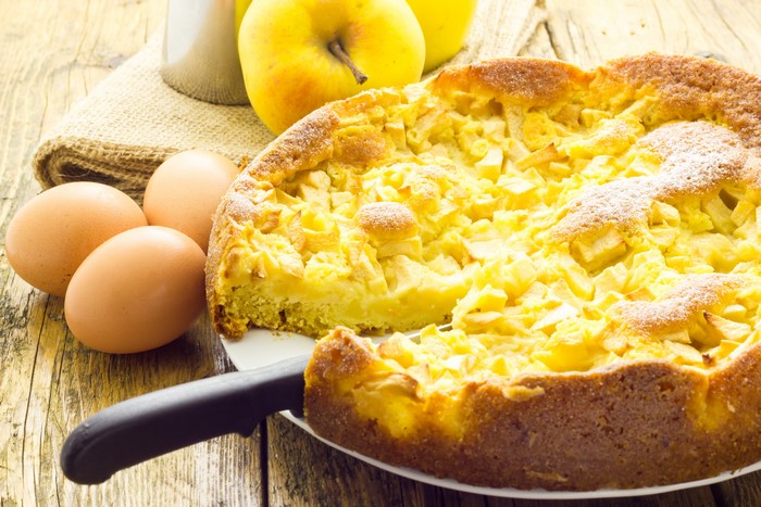 Apple pie with apples and eggs on a wooden table