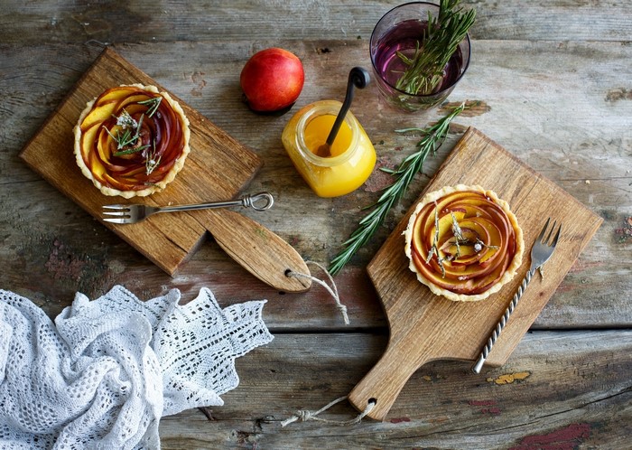 Two peach tarts with honey and rosemary on wooden boards