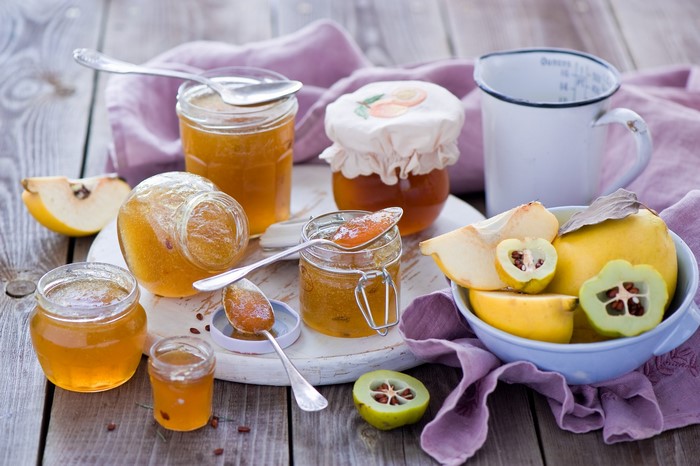Jars of quince jam with fresh quince fruits
