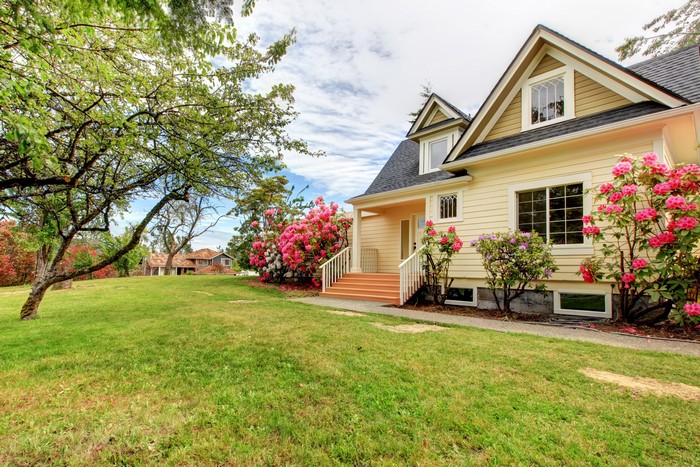 Yellow house with pink flowers and green lawn