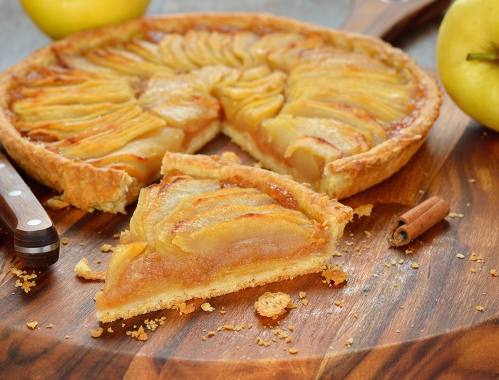 Apple pie with a slice on a wooden board