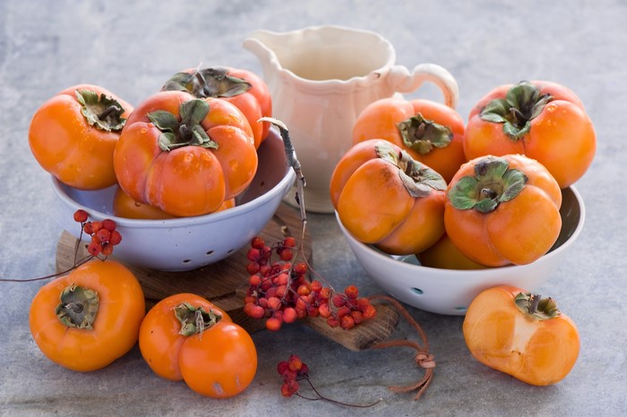 Persimmons in bowls with a pitcher and berries