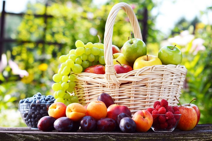 Fruit in a wicker basket with grapes, apples, and berries