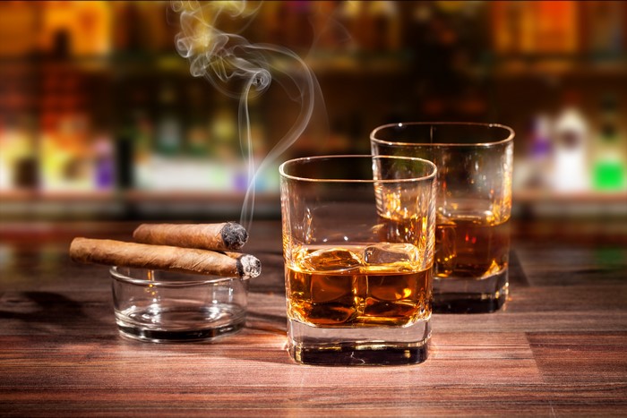 Two glasses of whiskey and cigars with smoke