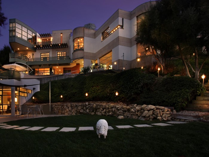 Modern house at night with lawn and sheep sculpture