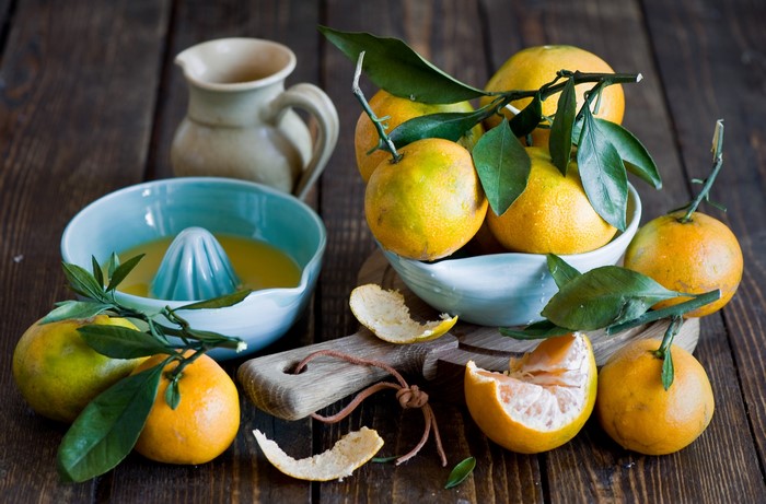 Oranges and citrus juicer on a wooden table
